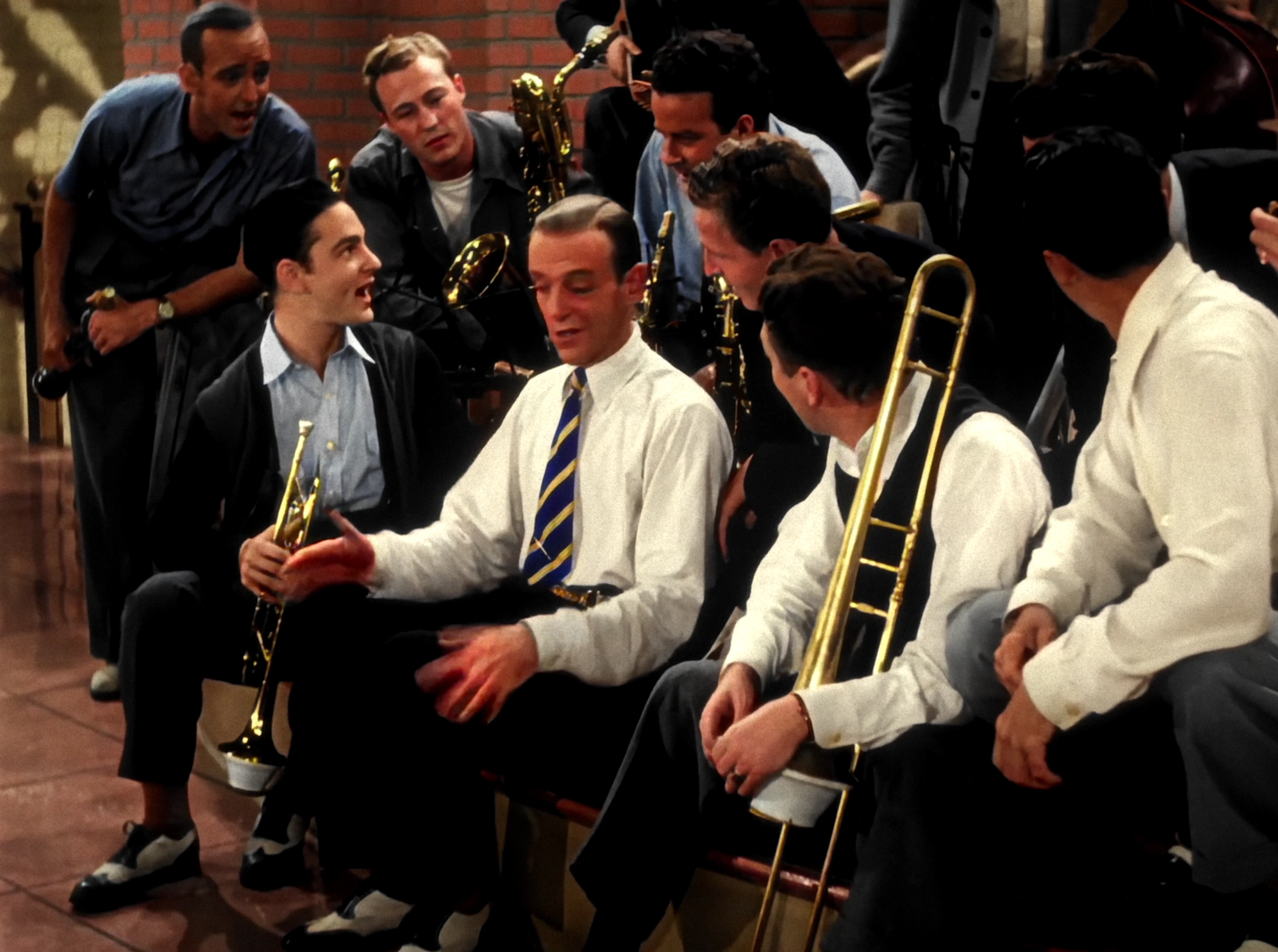 Colourised film still of musicians gathered with their instruments